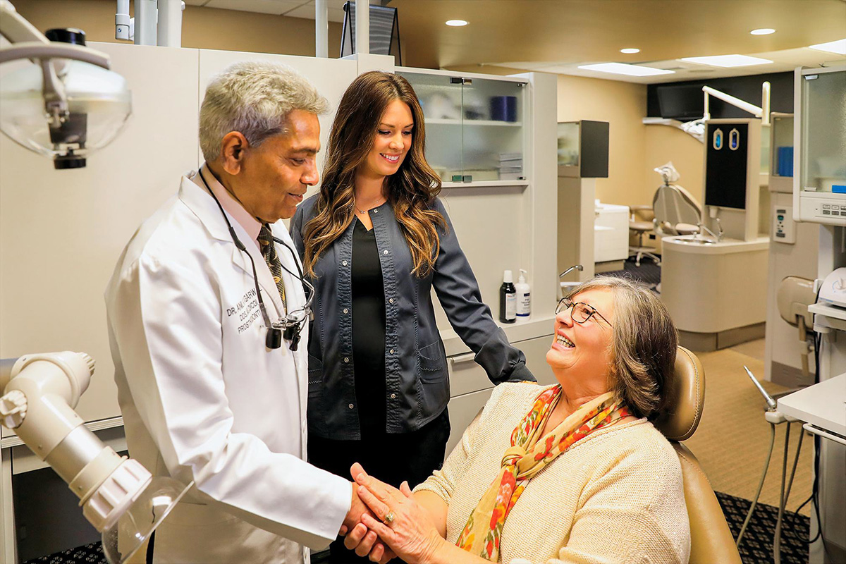 Dr. Agarwal shakes hands with a patient sitting on a dental chair
