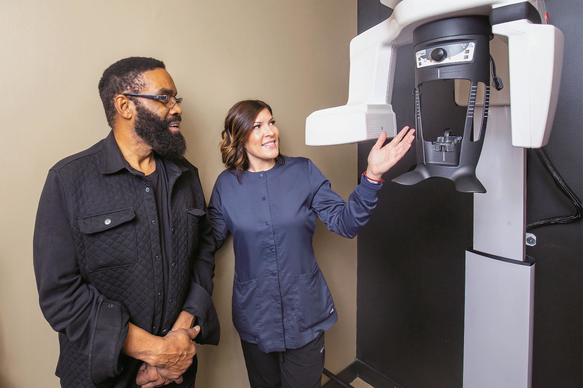 A dental assistant shows a patient a 3D scanner