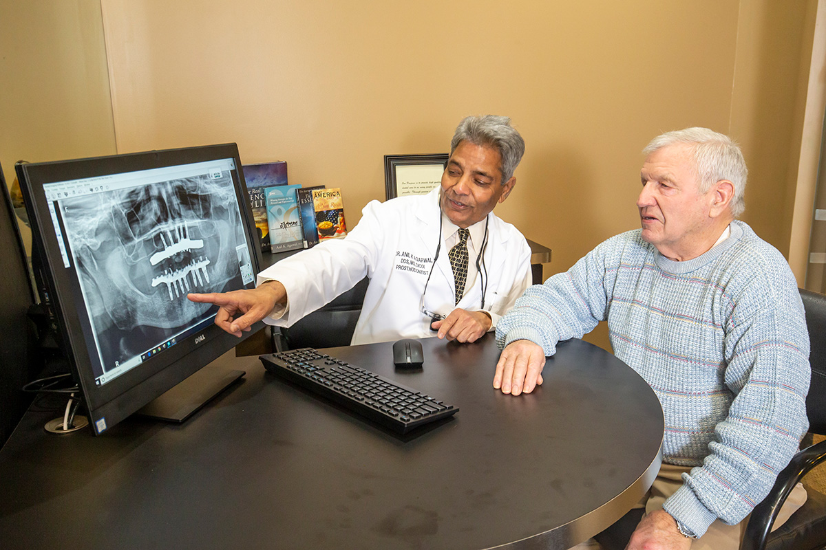 Dr. Agarwal shows a patient a teeth X-ray on a computer screen