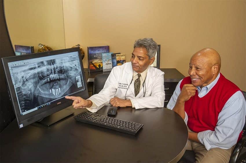 Dr. Agarwal in a consultation with a patient reviewing the All-on-4 <sup srcset=