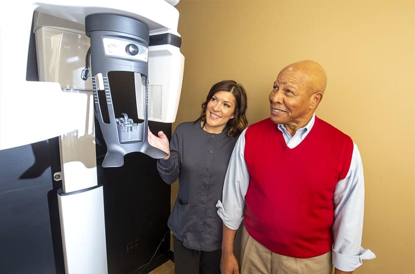 Patient being shown a 3D Cone Beam X-Ray machine before starting Full-Arch Teeth Replacement.